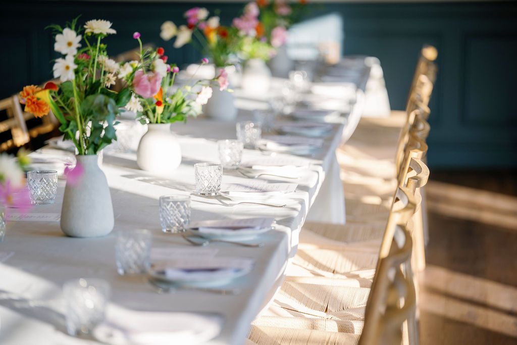 An intimate private-dining table set with wildflowers and candlelight, bathed in afternoon light