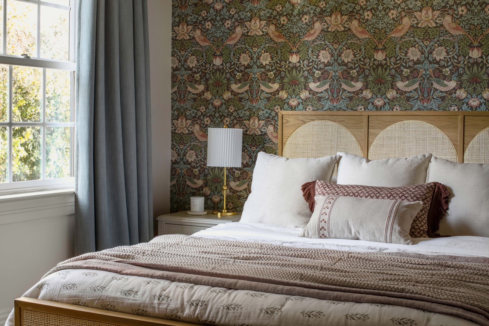 The Rose Bedroom at The Craft House Inn, with floral wallpaper and a cane headboard